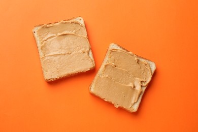 Photo of Tasty peanut butter sandwiches on orange background, flat lay