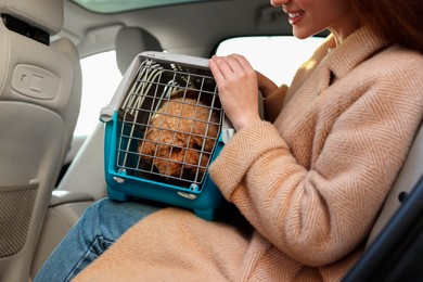 Photo of Smiling woman with pet carrier travelling with her dog by car, closeup