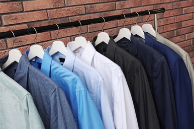 Photo of Wardrobe rack with stylish clothes near brick wall