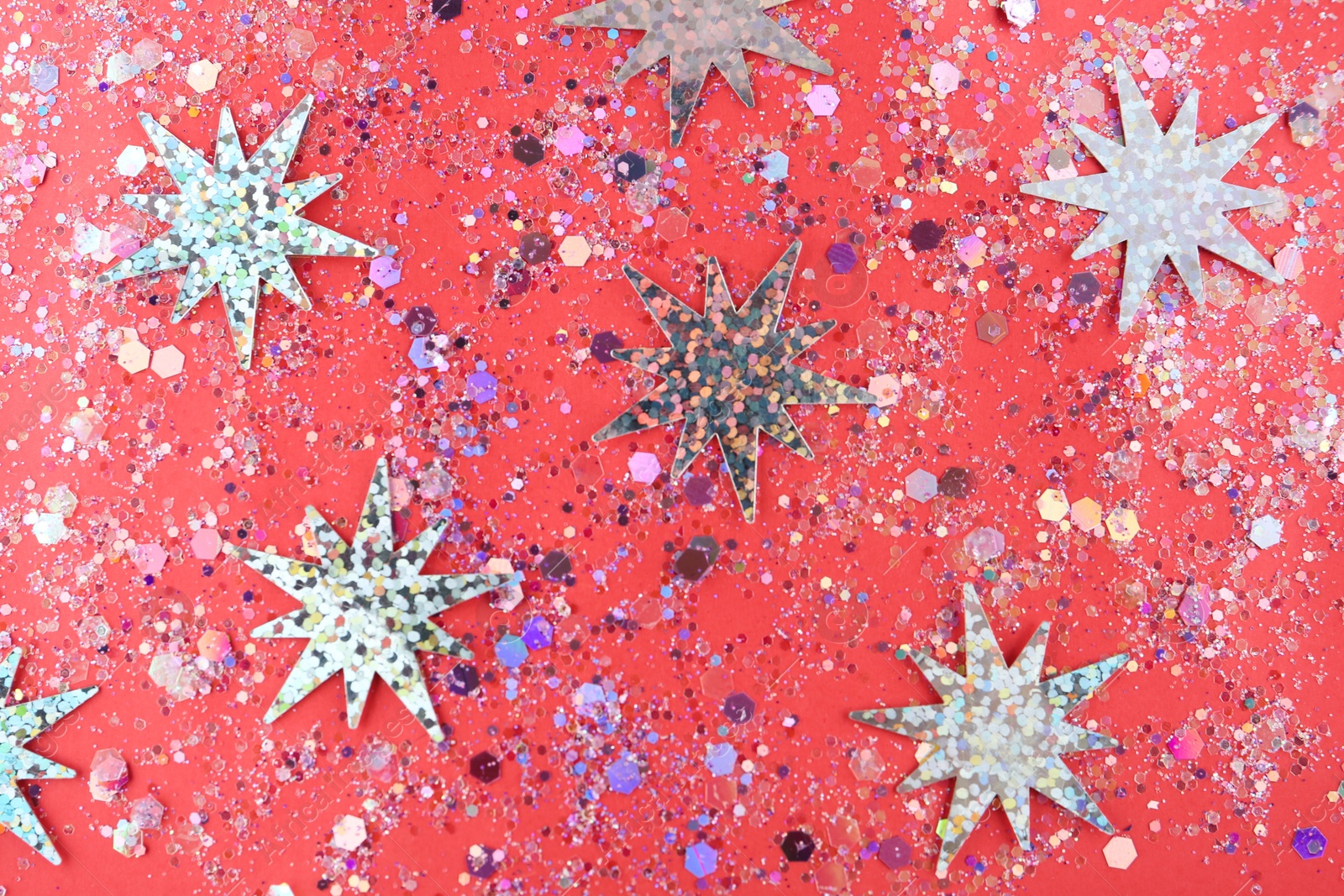 Photo of Shiny glitter on red background, flat lay