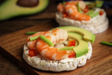 Puffed rice cakes with shrimps and avocado on wooden board, closeup