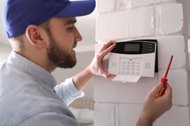 Photo of Man installing home security system on white wall in room