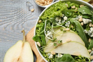 Photo of Fresh salad with pear on grey wooden table, closeup