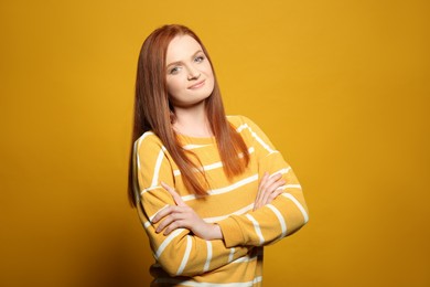 Photo of Candid portrait of happy young woman with charming smile and gorgeous red hair on yellow background