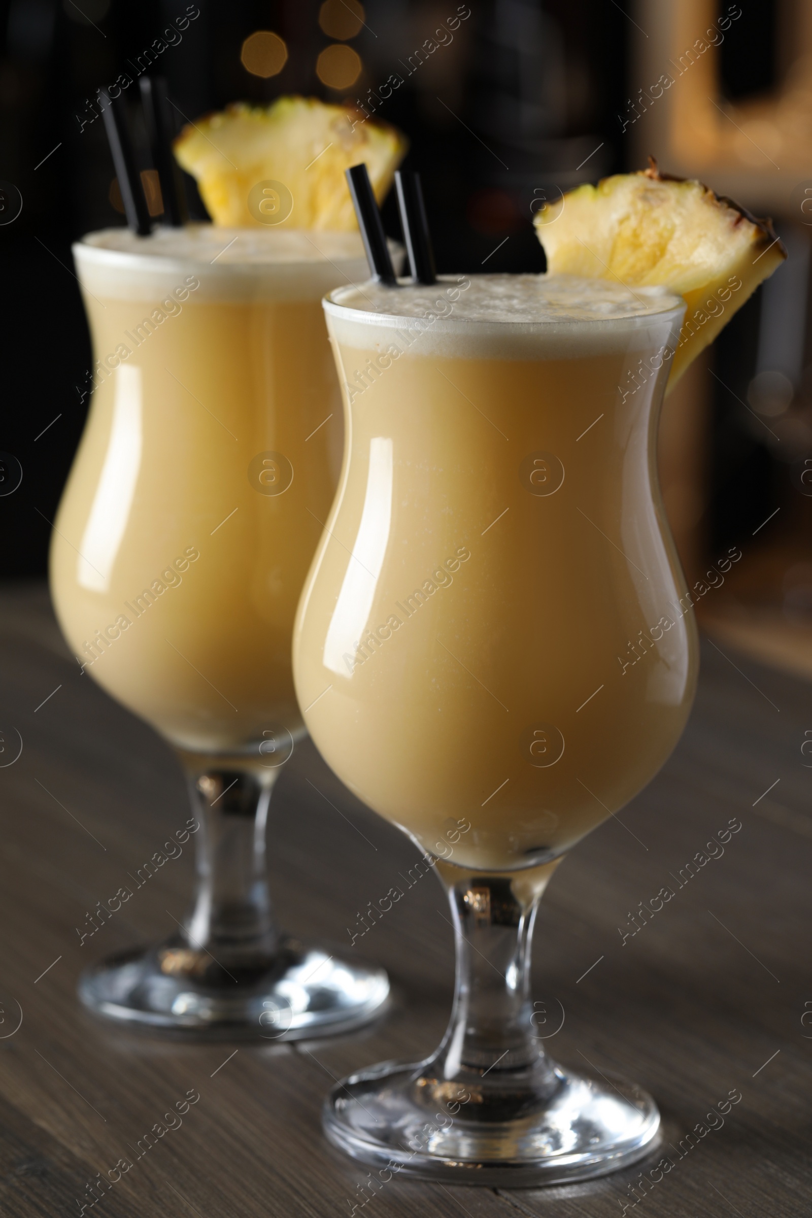 Photo of Tasty Pina Colada cocktails on wooden bar countertop