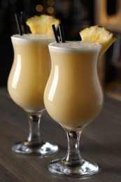 Tasty Pina Colada cocktails on wooden bar countertop