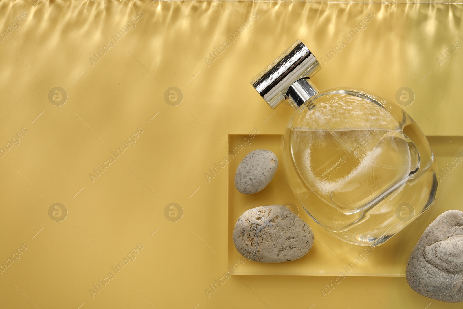 Photo of Stylish presentation of luxury perfume in bottle on golden background, flat lay. Space for text