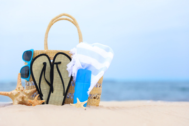 Photo of Bag and beach objects on sand near sea, space for text