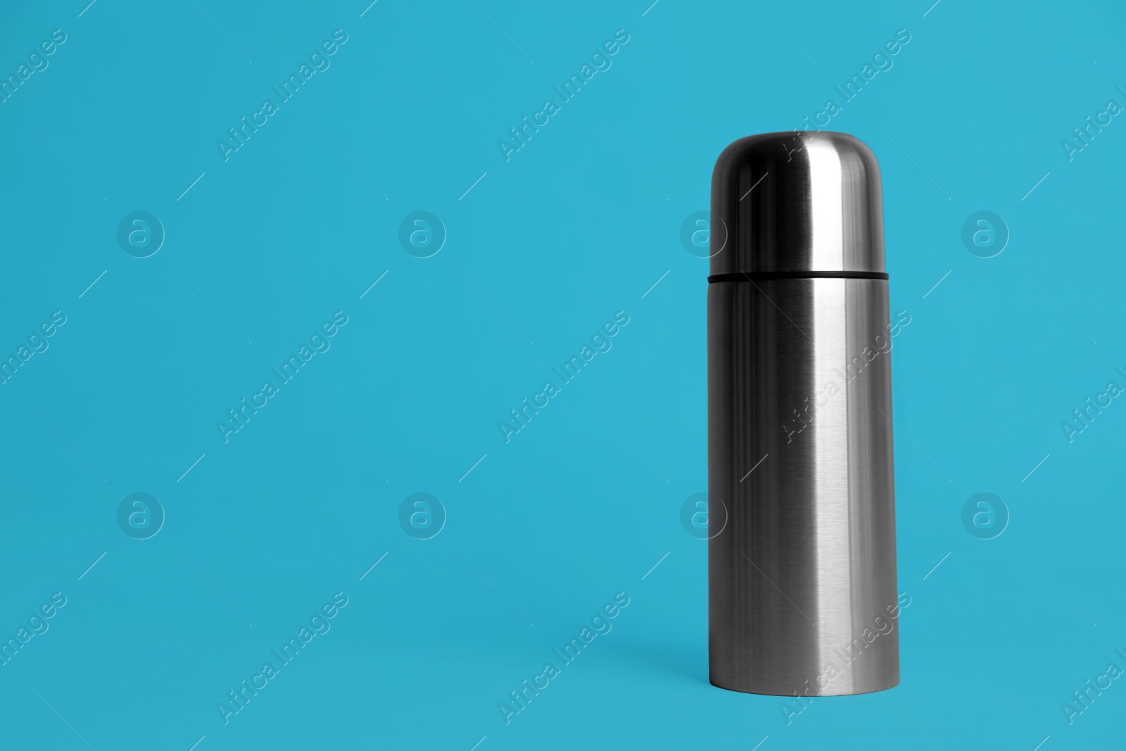 Photo of Stylish thermo bottle on light blue background, space for text