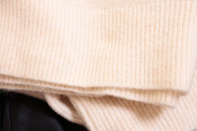 Photo of Soft beige sweater on black fabric, above view