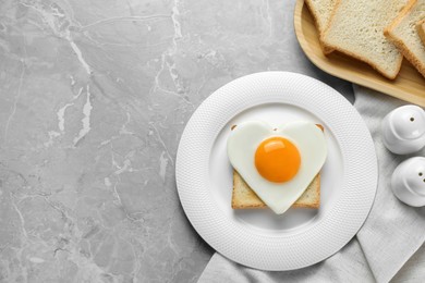 Photo of Heart shaped fried egg served on grey marble table, space for text