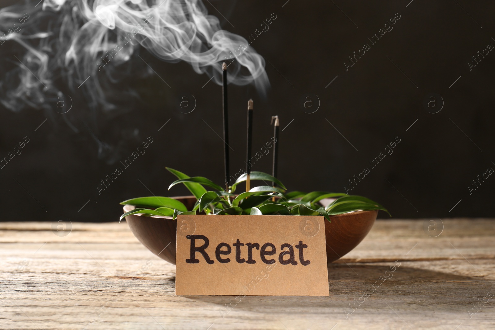 Photo of Card with word Retreat, green leaves and incense sticks on wooden table