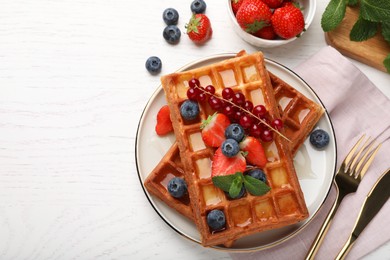 Photo of Delicious Belgian waffles with berries served on white wooden table, flat lay. Space for text