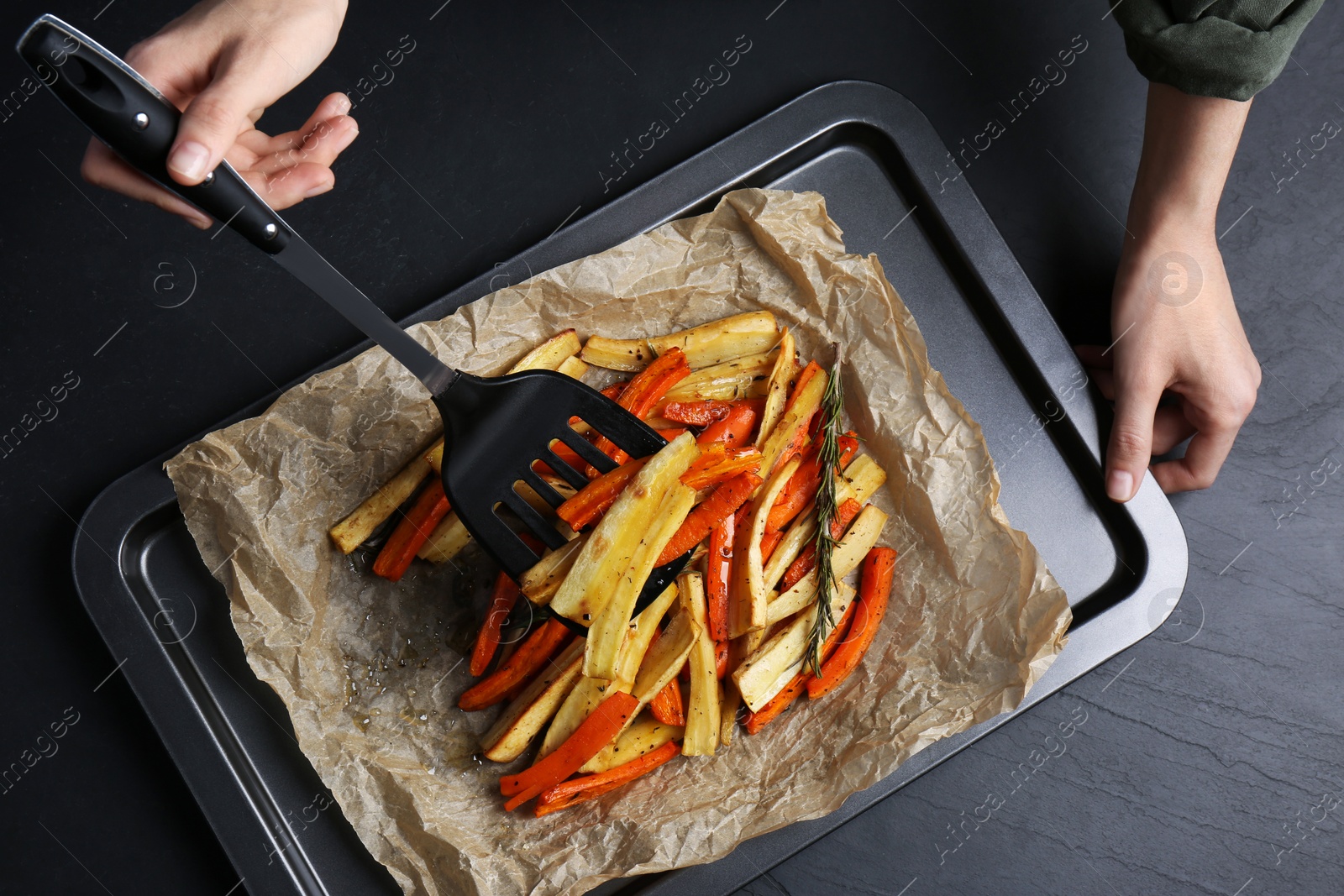 Photo of Cooker near baking pan with tasty parsnip and bell pepper at dark grey table, top view