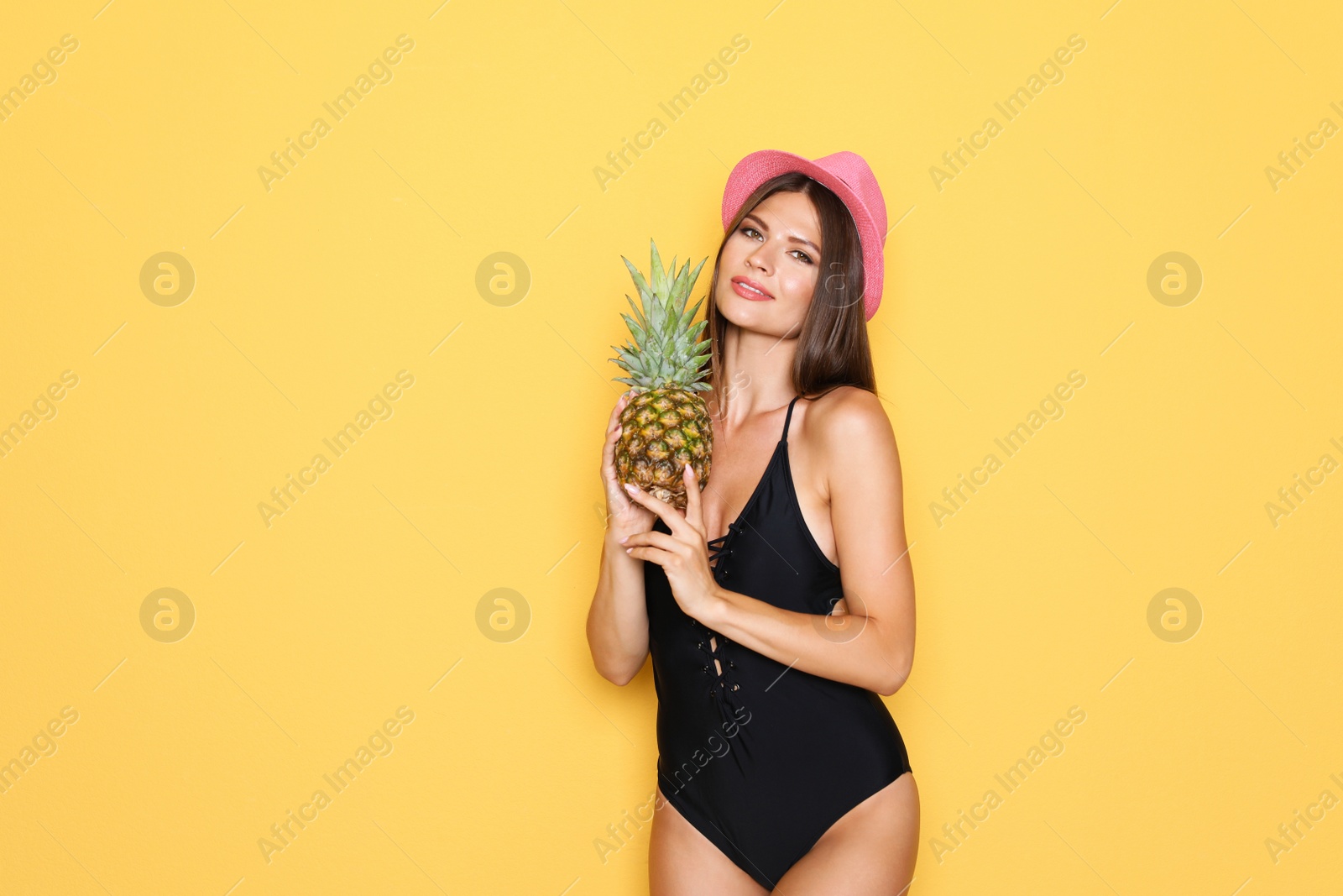 Photo of Sexy young woman in bikini with pineapple on color background