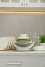 Clean plates, cup, glasses and butter dish on white countertop in kitchen