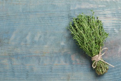 Bunch of aromatic thyme on light blue wooden table, top view. Space for text