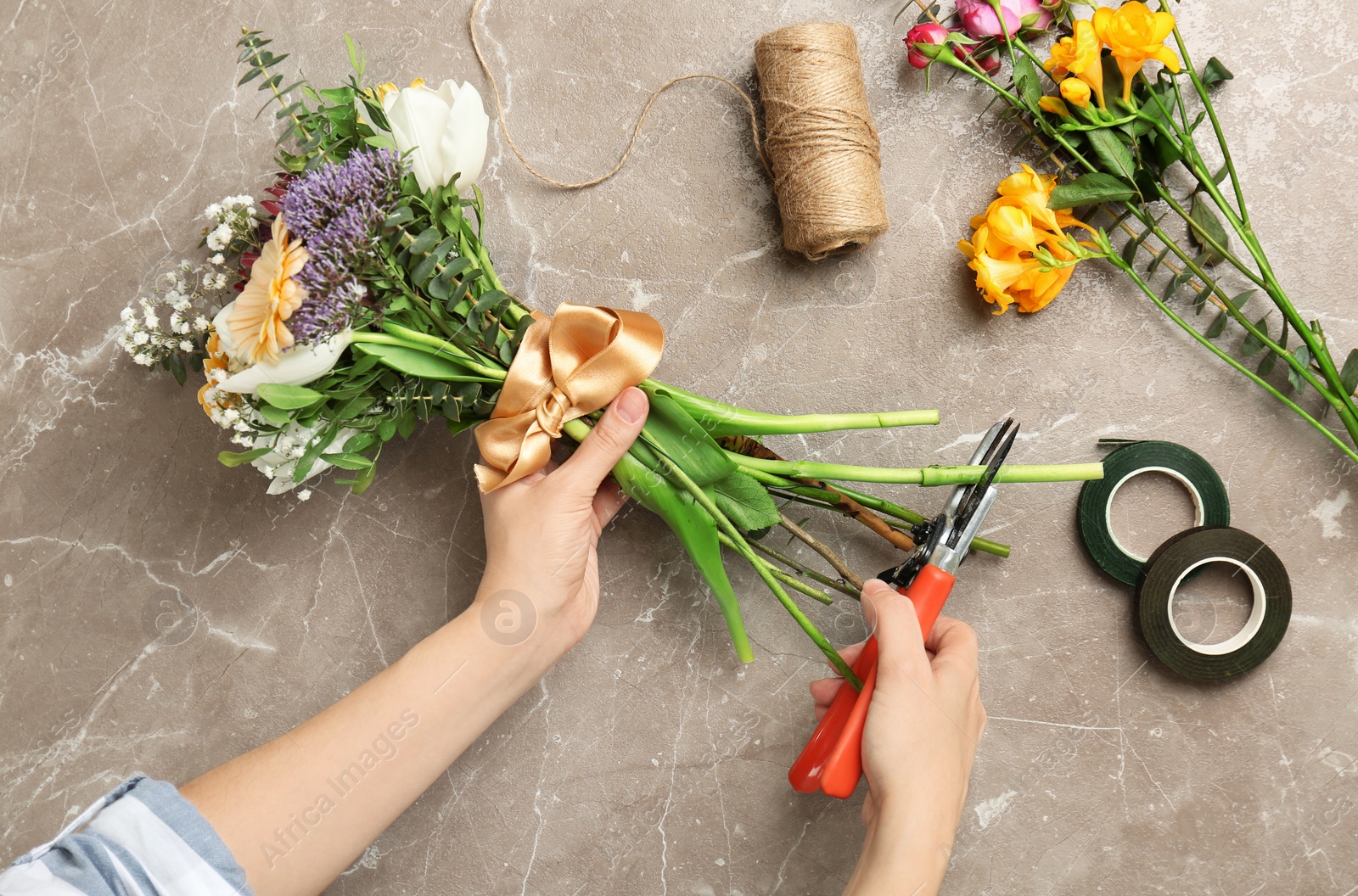 Photo of Female florist pruning stem at table, top view