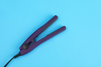 Photo of Modern hair iron for straightening on color background, top view