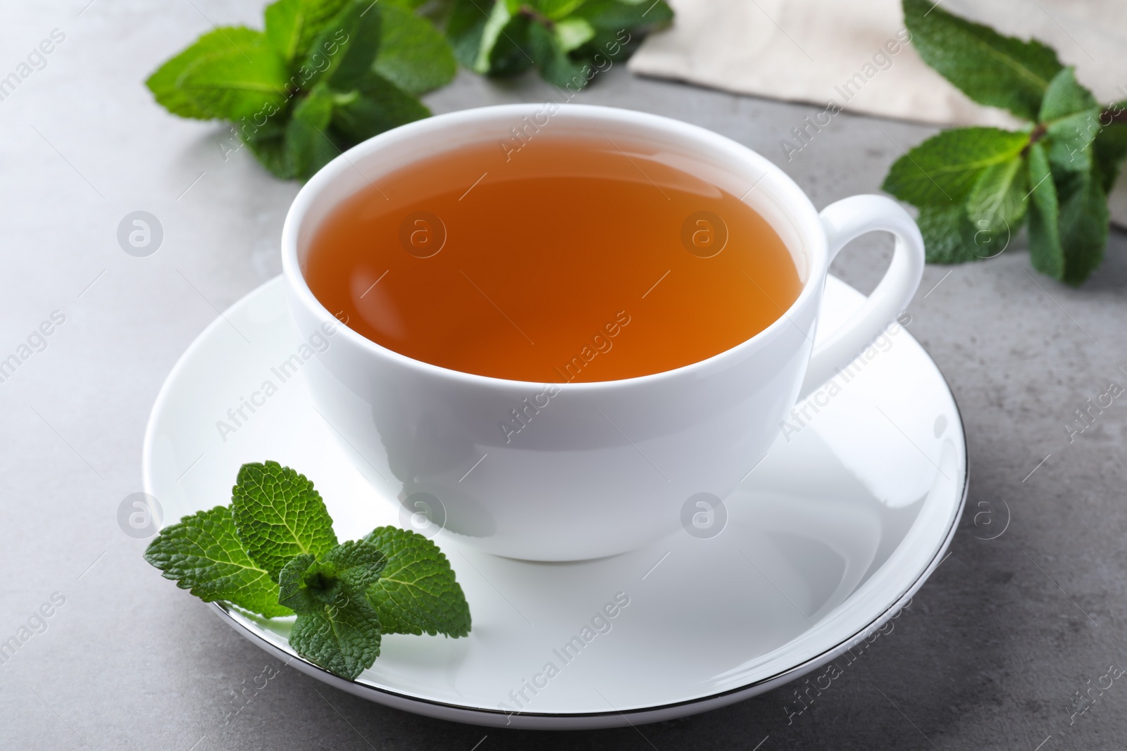 Photo of Cup of hot aromatic mint tea on light grey table