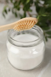 Photo of Bamboo toothbrush and jar of baking soda on table, closeup