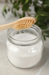 Bamboo toothbrush and jar of baking soda on table, closeup