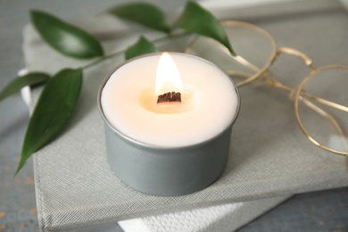 Burning candle with wooden wick on grey table