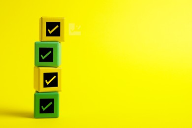 Image of Stacked cubes with check marks on yellow background. Space for text
