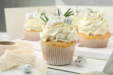 Photo of Tasty Easter cupcakes with vanilla cream on white marble table