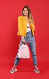 Photo of Happy woman with backpack on red background