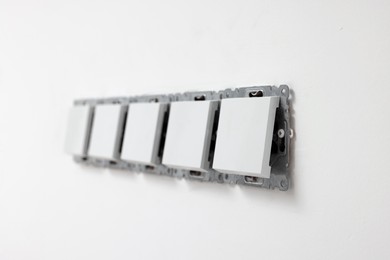 Photo of Modern plastic switches on white wall. Installing lighting