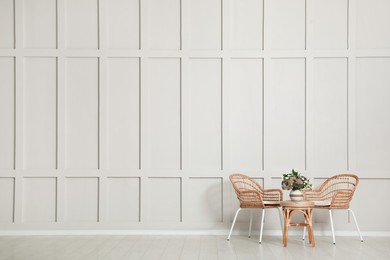 Simple room interior with set of wicker furniture, beautiful flowers and empty wall. Space for design