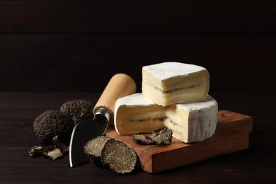 Photo of Delicious cheese, fresh black truffles and knife on wooden table