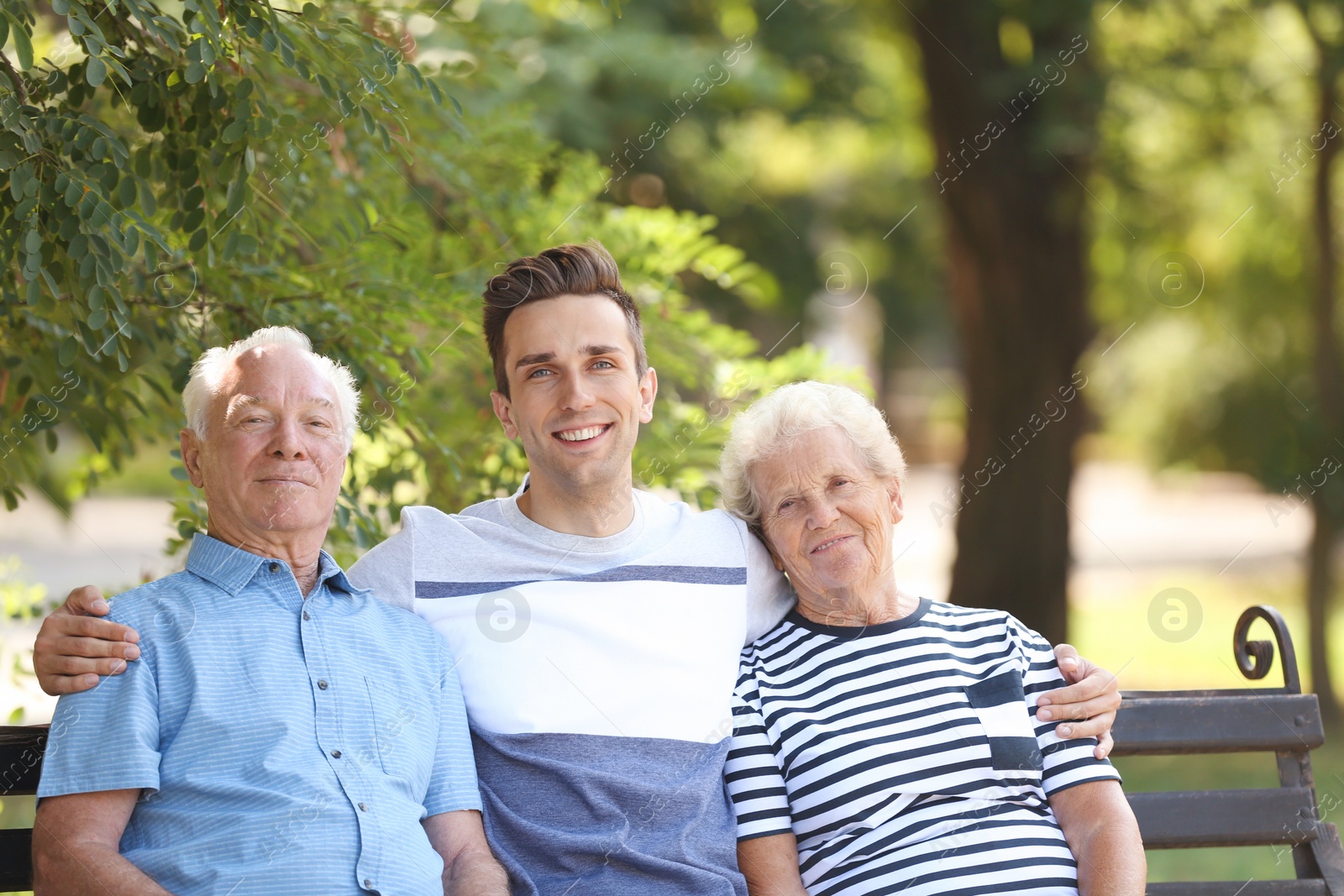 Photo of Man with elderly parents on bench in park