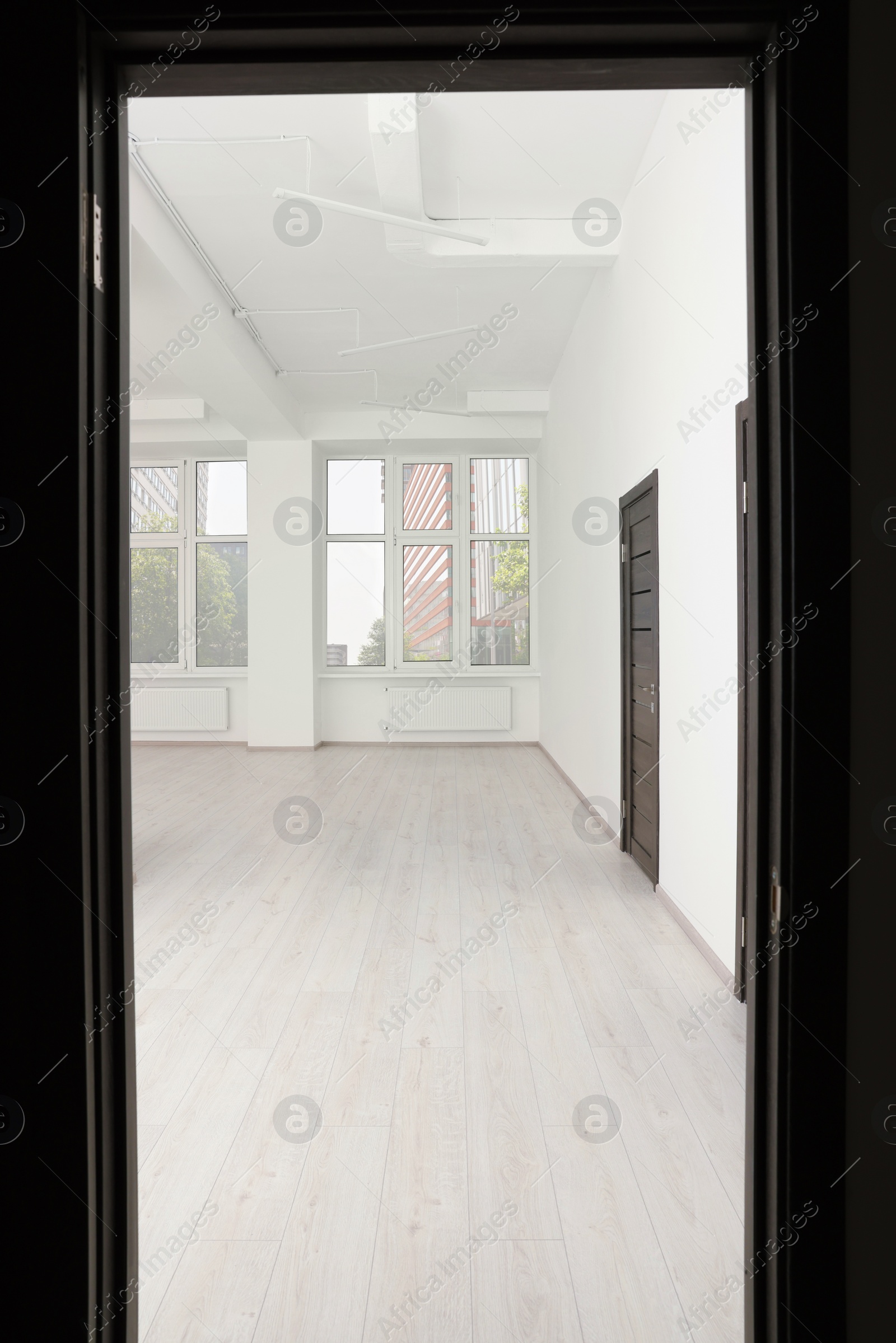Photo of Modern office room with windows and door, view from entrance. Interior design