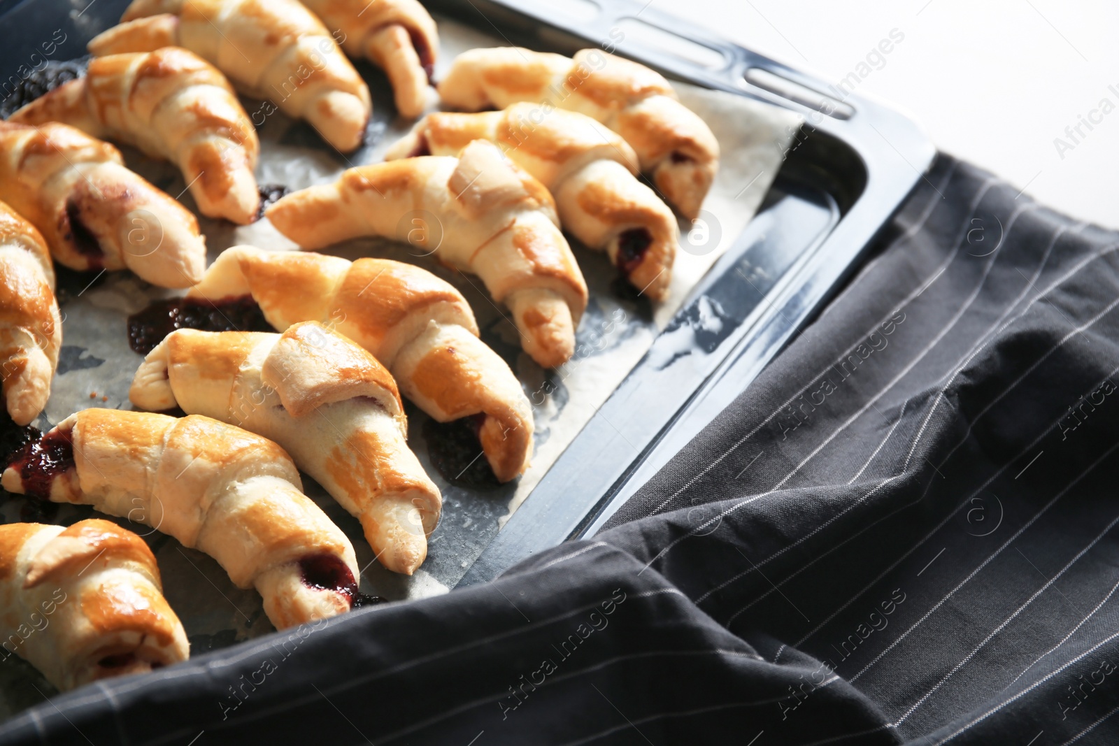 Photo of Tasty croissants on baking sheet on table