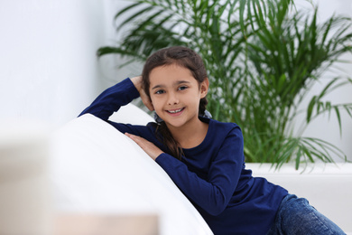Photo of Cute little girl on sofa in living room
