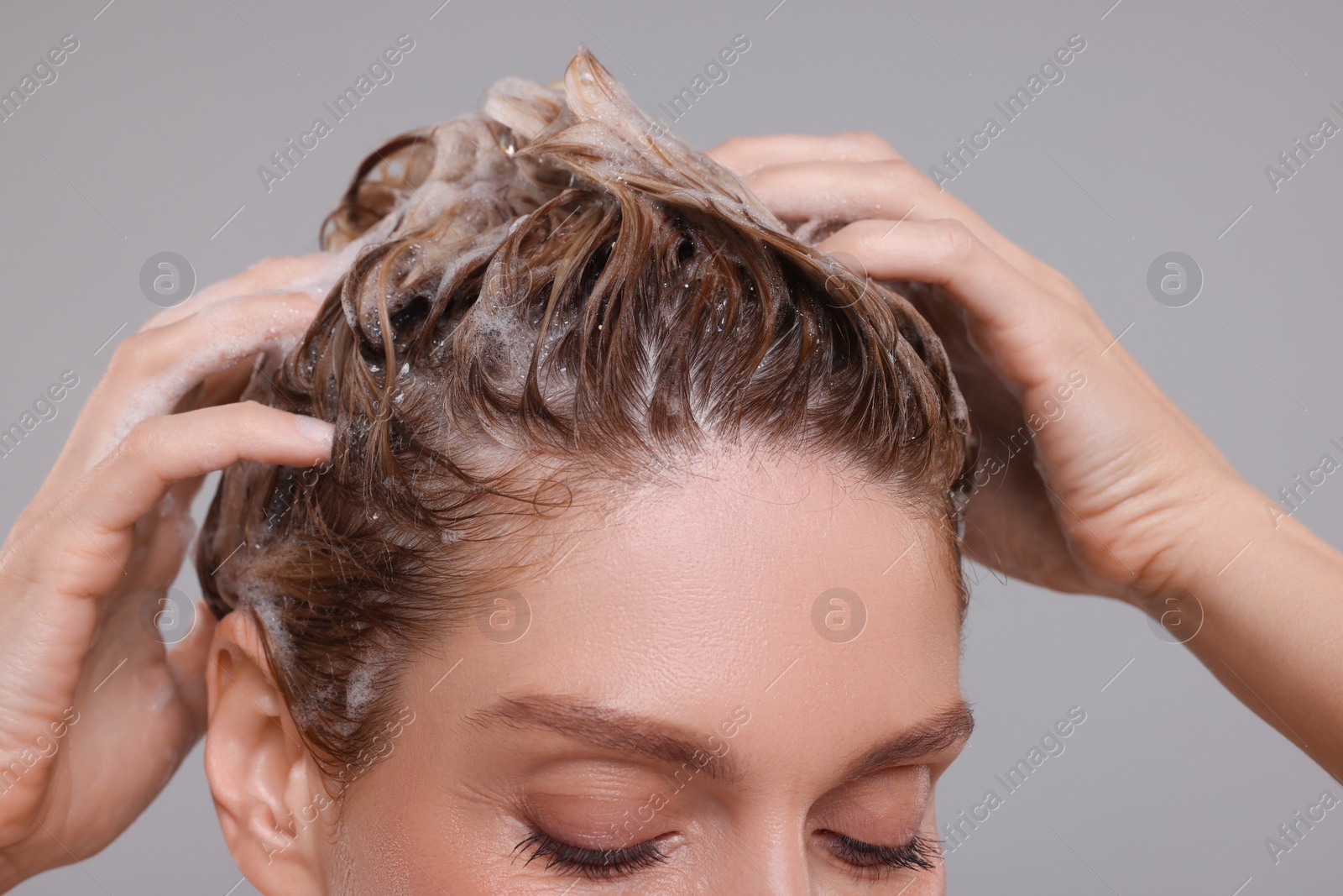 Photo of Woman washing hair on light grey background, closeup