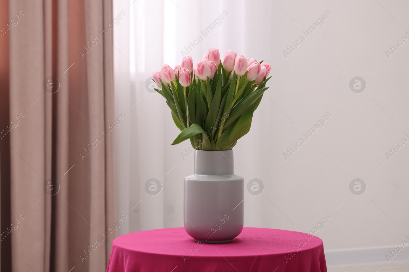 Photo of Beautiful bouquet of fresh pink tulips on table indoors