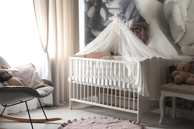 Photo of Baby room interior with stylish crib and floral wallpaper