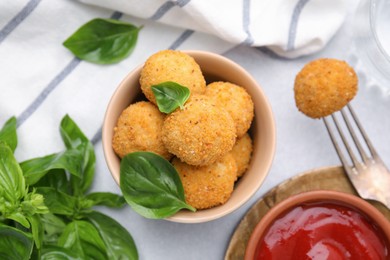 Photo of Bowl of delicious fried tofu balls with basil and ketchup on white table, flat lay