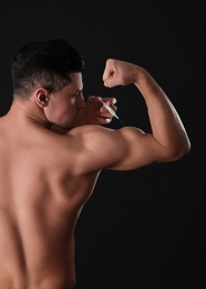 Photo of Athletic man injecting himself on black background. Doping concept