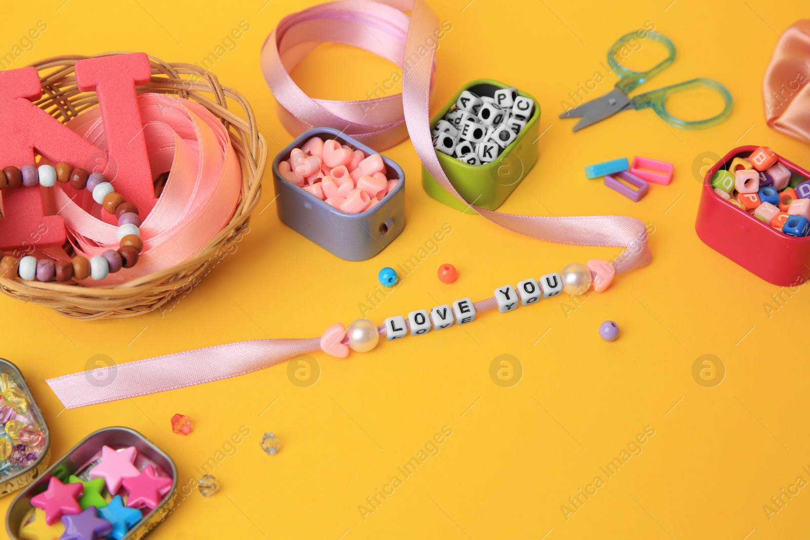 Photo of Handmade jewelry kit for kids. Colorful beads, ribbon, bracelet and different supplies on orange background