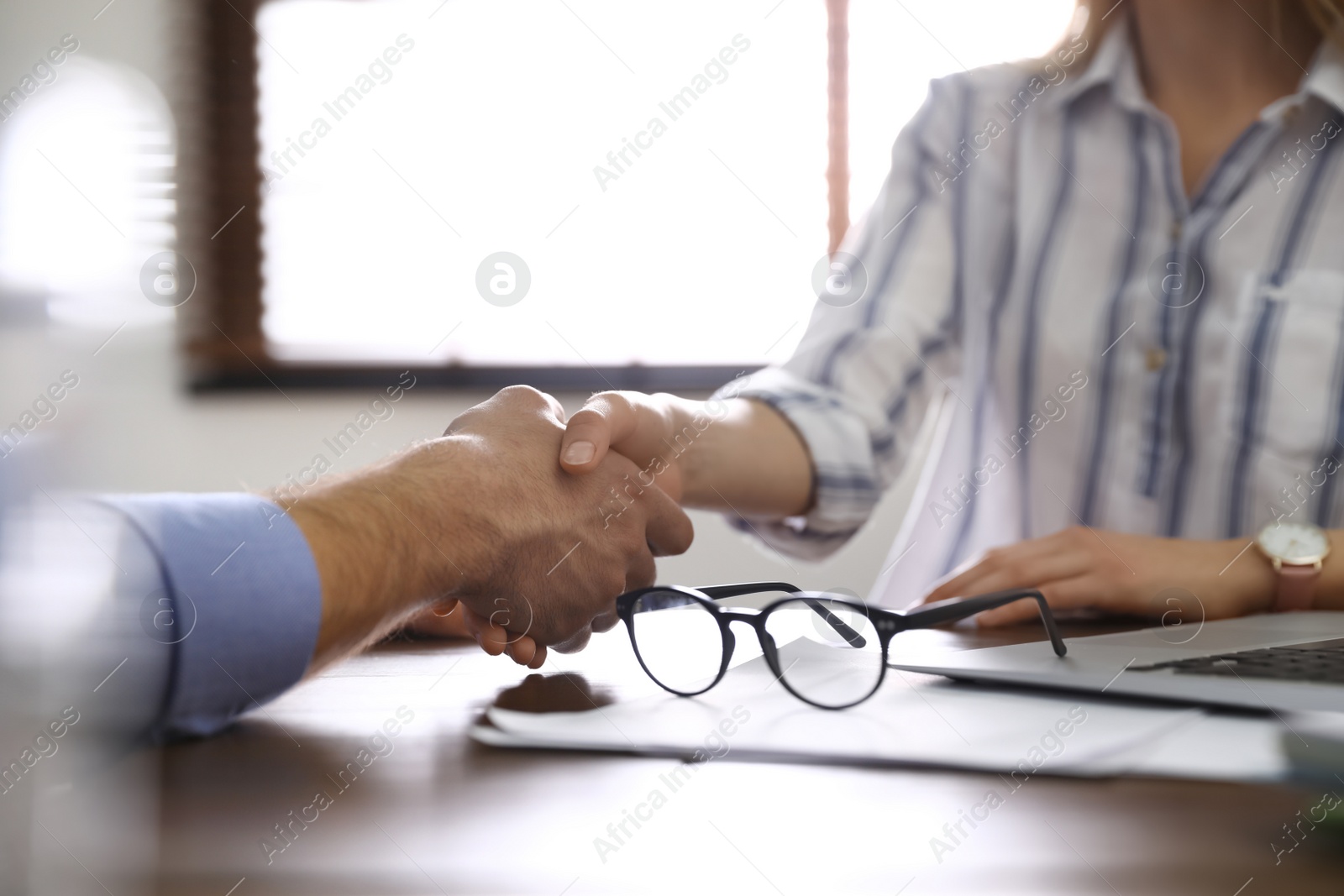 Photo of Business partners shaking hands at table after meeting in office, closeup