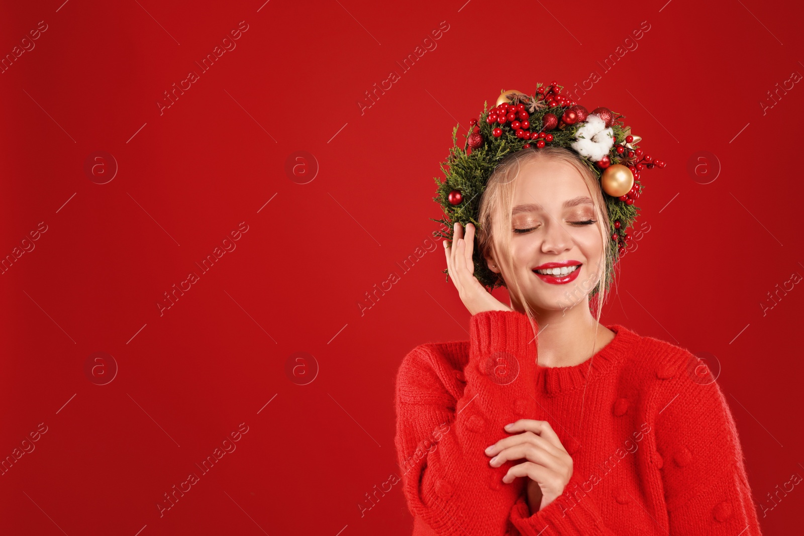 Photo of Beautiful young woman wearing Christmas wreath on red background. Space for text