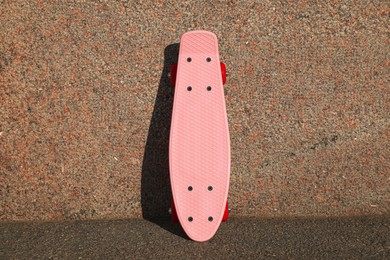 Photo of Pink skateboard with red wheels near wall outdoors