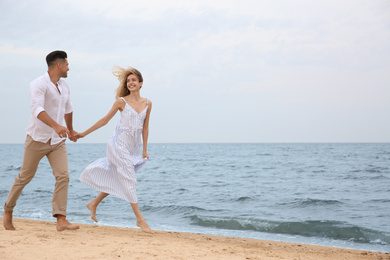 Photo of Happy couple running on beach, space for text. Romantic walk