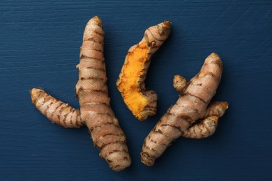 Raw turmeric roots on blue wooden table, flat lay