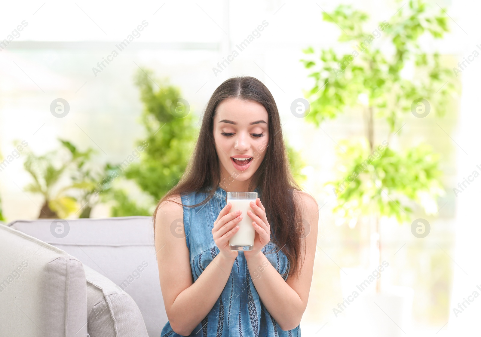 Photo of Beautiful young woman drinking milk at home