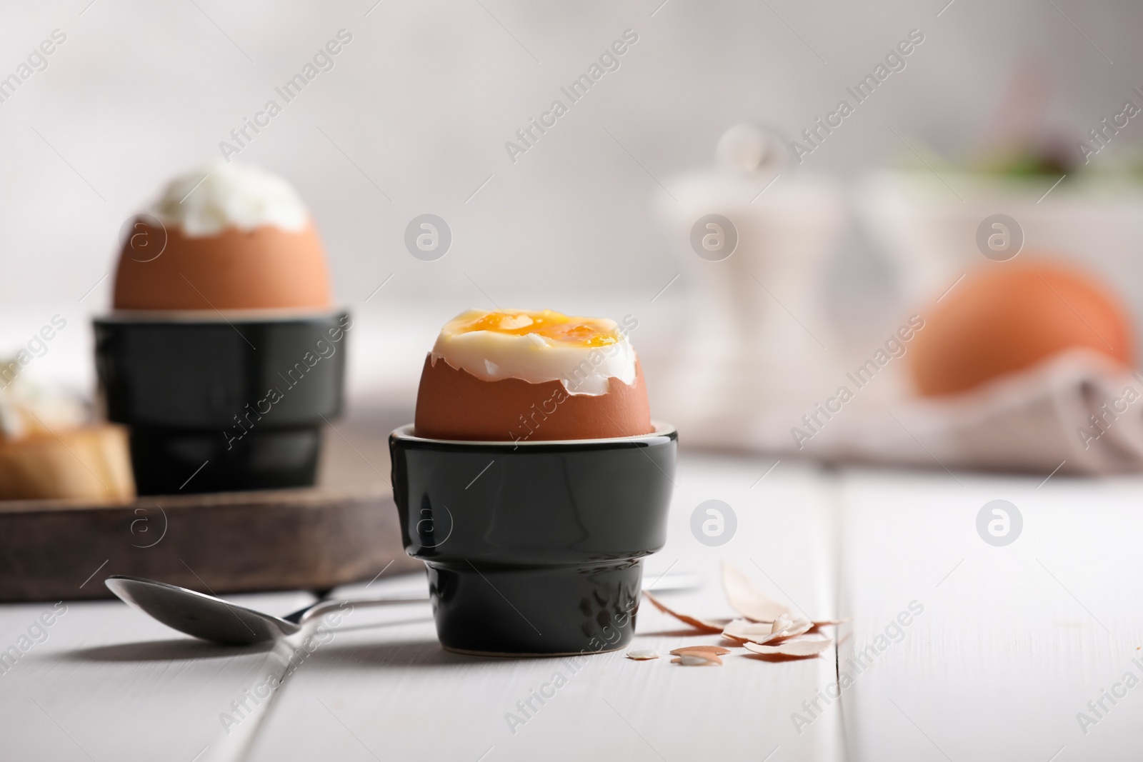 Photo of Fresh soft boiled egg in cup served on white wooden table. Space for text